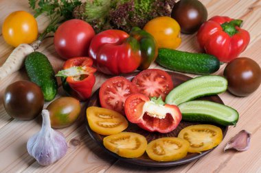 Domatesli sebze, tatlı biber ve ahşap bir masa üzerinde salatalık.