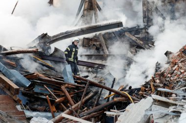 ZHYTOMYR, UKRAINE - 8 Mart 2022: Rusya 'nın Ukrayna' ya karşı savaşı. Kiev yakınlarındaki büyük bir şehirde, düşman uçakları ve füzeleri bir eve zarar veriyor. İtfaiyeciler yangını söndürdü. Kurtarma ekipleri evin enkazını sökün..