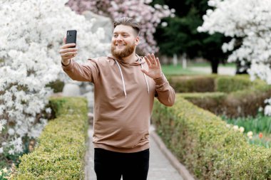 Adam manolyanın arka planında neşeyle selfie çekiyor. Video aracılığıyla iletişim kuruyor. Çevresini gösteriyor..