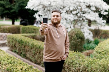 Adam manolyanın arka planında neşeyle selfie çekiyor. Video aracılığıyla iletişim kuruyor. Çevresini gösteriyor..