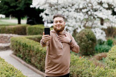 Adam manolyanın arka planında neşeyle selfie çekiyor. Video aracılığıyla iletişim kuruyor. Çevresini gösteriyor..