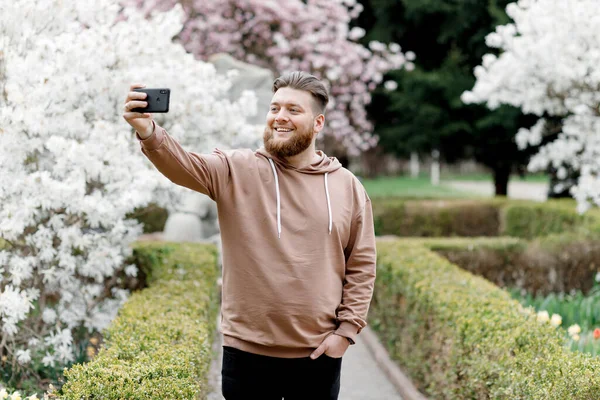 Adam manolyanın arka planında neşeyle selfie çekiyor. Video aracılığıyla iletişim kuruyor. Çevresini gösteriyor..