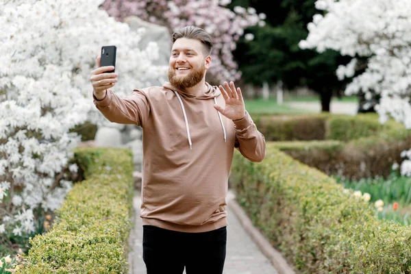 Adam manolyanın arka planında neşeyle selfie çekiyor. Video aracılığıyla iletişim kuruyor. Çevresini gösteriyor..