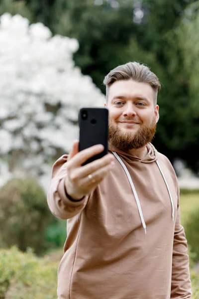 Adam manolyanın arka planında neşeyle selfie çekiyor. Video aracılığıyla iletişim kuruyor. Çevresini gösteriyor..