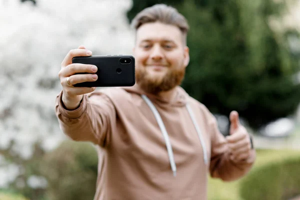 Adam manolyanın arka planında neşeyle selfie çekiyor. Video aracılığıyla iletişim kuruyor. Çevresini gösteriyor..