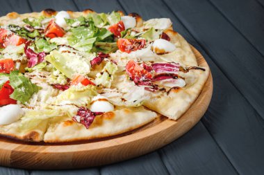 Gri ahşap arka planda pizza, yan görüş, yakın çekim. Peynirli, soslu, domatesli, parmesanlı, bıldırcın yumurtalı lahana, salata, tavuk göğsü, mozzarella. metin için yer.