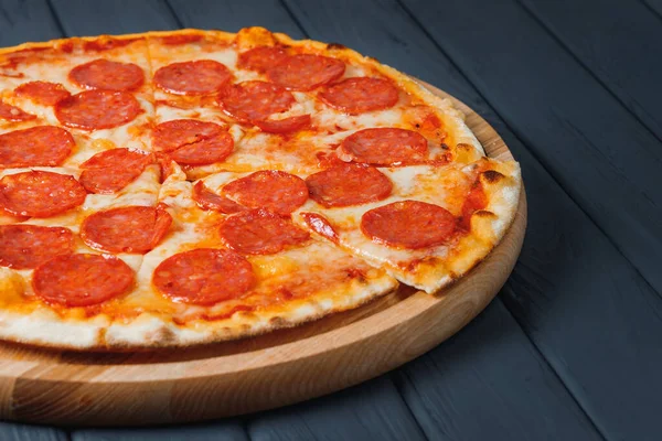 Gri ahşap arka planda pizza, yan görüş, yakın çekim. Napolitan soslu pizza, mozzarella peyniri, pepperoni. metin için yer.