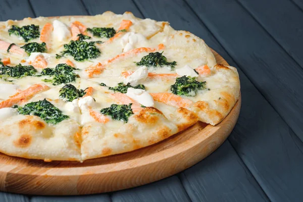 Gri ahşap arka planda pizza, yan görüş, yakın çekim. Peynirli pizza, sos, balık, ıspanak, somon, mozzarella, krem peynir. metin için yer.
