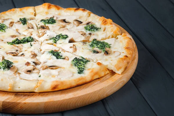 Gri ahşap arka planda pizza, yan görüş, yakın çekim. Peynirli pizza, sos, mantar, ıspanak, jambon. metin için yer.