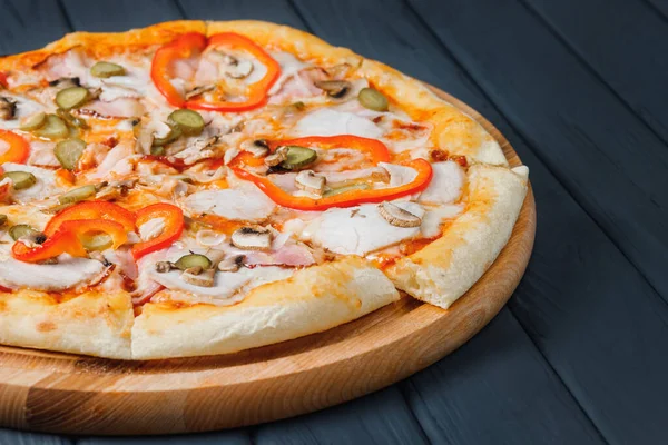 Gri ahşap arka planda pizza, yan görüş, yakın çekim. Peynirli, soslu, salatalıklı, mantarlı, biberli, jambonlu, balyklı, soğanlı pizza. metin için yer.