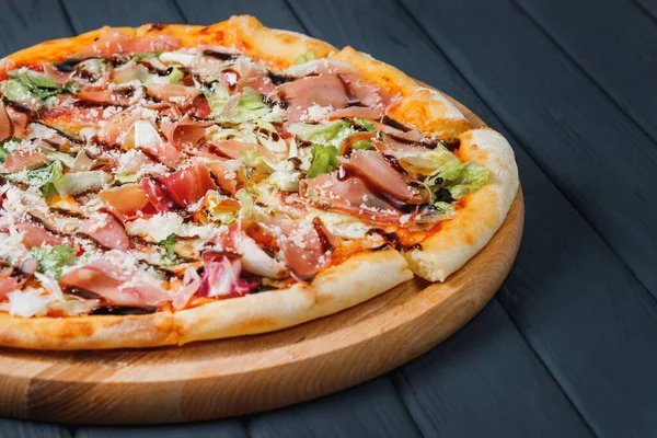 Gri ahşap arka planda pizza, yan görüş, yakın çekim. Peynirli pizza, parmesan peyniri, jambon, sos, salata, lahana. metin için yer.