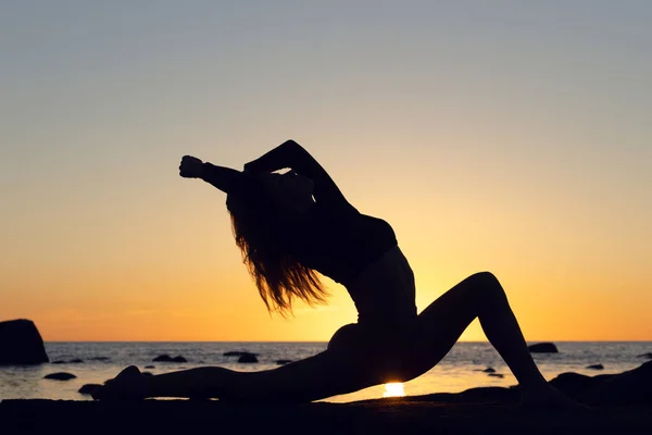 Γυναίκα που κάνει εξάσκηση στο ηλιοβασίλεμα. παραθαλάσσιο φόντο, σιλουέτα — Φωτογραφία Αρχείου