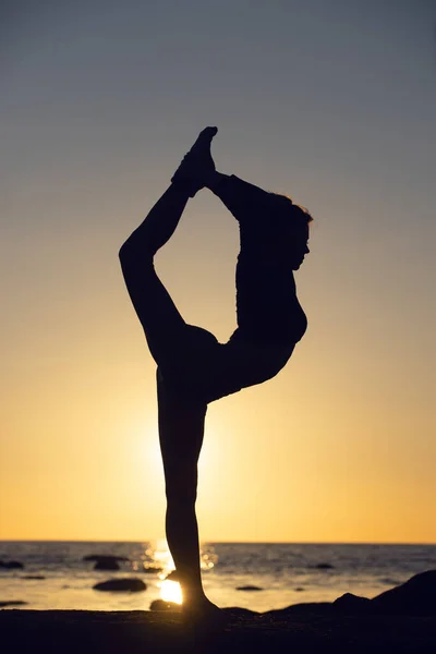 Kvinna tränar stretching vid solnedgången. havet bakgrund, silhuett — Stockfoto