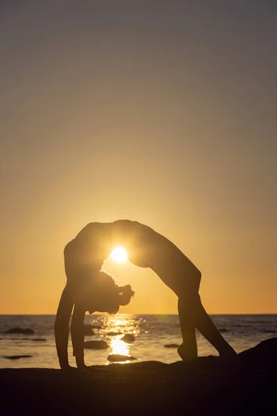 Frau übt Stretching bei Sonnenuntergang. Meer Hintergrund, Silhouette — Stockfoto