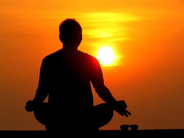 Bir adam bir yana bir yana güneş gözlüklerini tutulması ve r üzerinde meditasyon — Stok fotoğraf