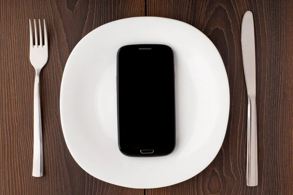 Mobile phone on a white plate — Stock Photo, Image
