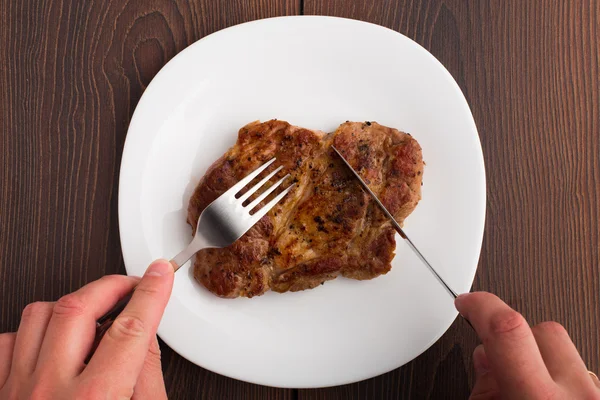 Alguien comiendo filete a la parrilla en un plato blanco —  Fotos de Stock