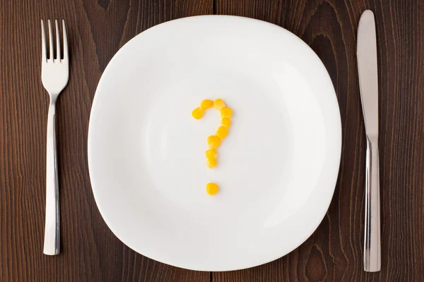 Question mark made of corn seeds on plate — Stock Photo, Image