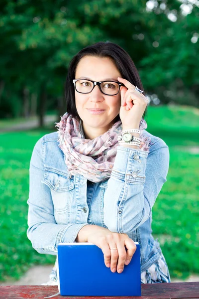 Beautiful young woman with book in park — Stock Photo, Image