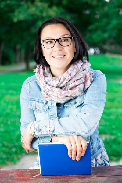 Vacker ung kvinna med bok i parken — Stockfoto