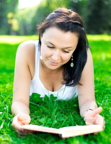 Schönes Mädchen auf einem Gras liegend mit Buch — Stockfoto
