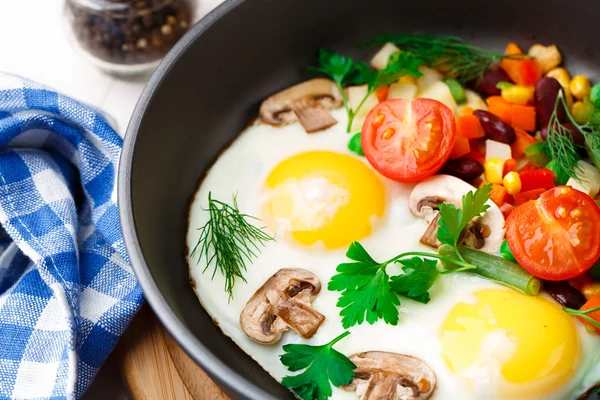 Fried eggs in a pan with vegetables — Stock Photo, Image