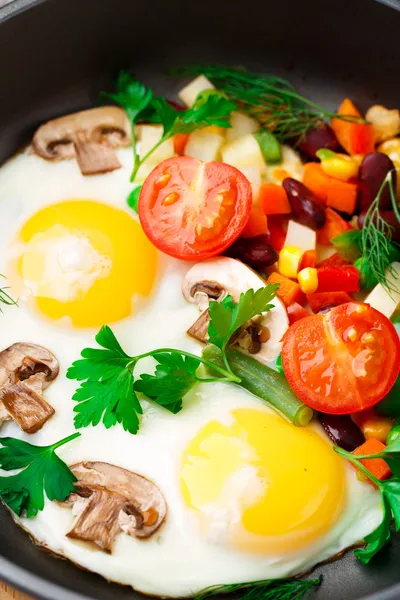 Fried eggs in a pan with vegetables — Stock Photo, Image