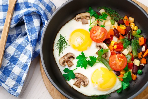 Fried eggs in a pan with vegetables — Stock Photo, Image