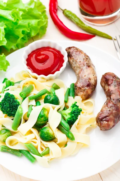 Fettuccine with vegetables and fried sausages — Stock Photo, Image