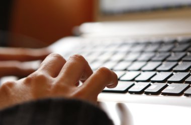 Dizüstü bilgisayarda çalışan genç bir kadın.