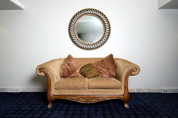 Eleganta soffan mot vägg med spegel Royaltyfria Stockbilder