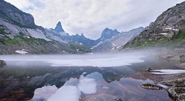 Mountain landscape. Mist over lake with ice clipart