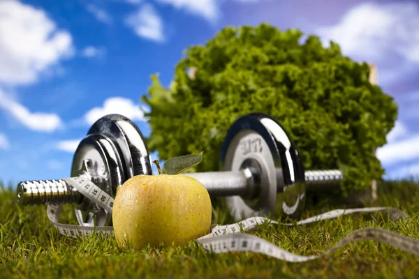 Vitamine en fitness dieet, dumbell in groene gras — Stockfoto