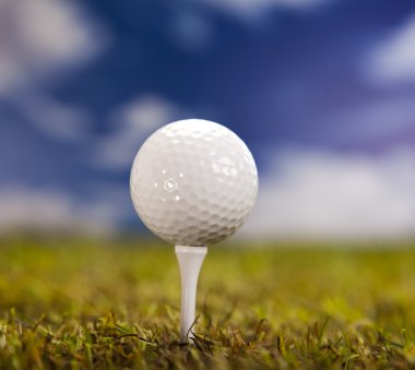 Golf topu mavi gökyüzü üzerinde yeşil çimenlerin üzerinde