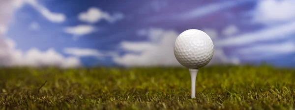 Golfball auf grünem Gras über blauem Himmel — Stockfoto