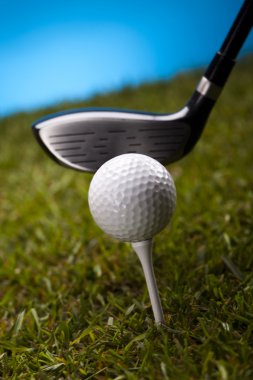 Golf topu mavi bir arka plan üzerinde yeşil çimenlerin üzerinde