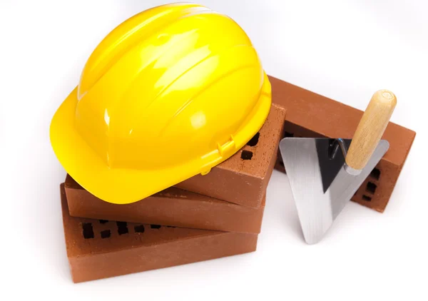 Hard hat with bricks and trowel — Stock Photo, Image