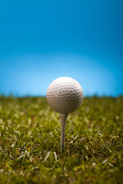 Golfball auf grünem Gras vor blauem Hintergrund — Stockfoto