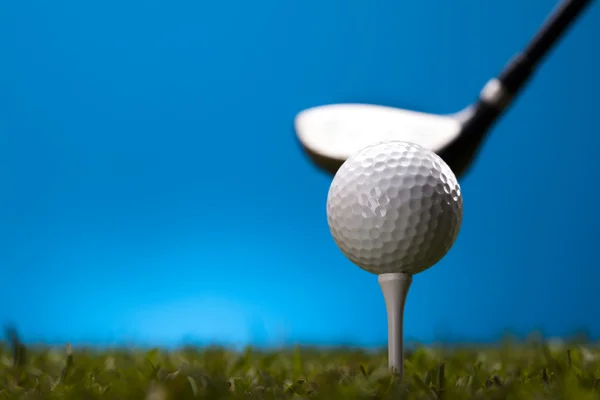 Pelota de golf sobre hierba verde sobre fondo azul — Foto de Stock
