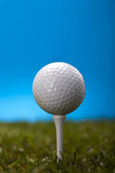 Golfboll på grönt gräs över en blå bakgrund — Stockfoto