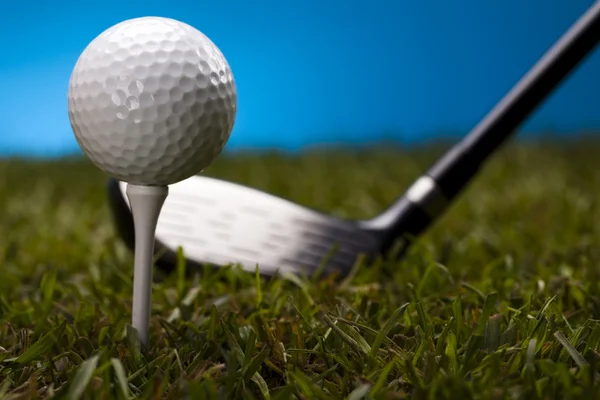 Bola de golfe na grama verde sobre um fundo azul — Fotografia de Stock