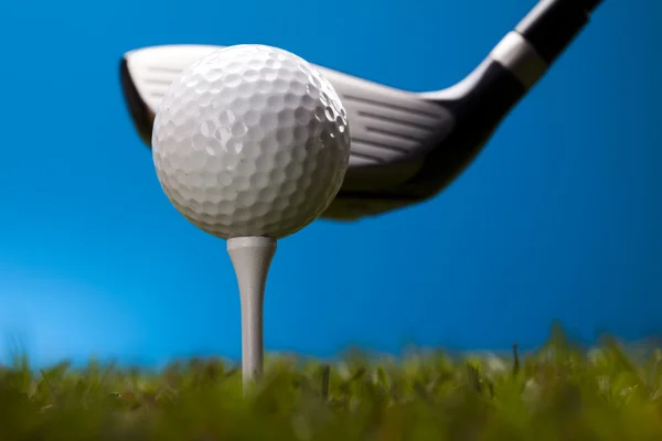 Pelota de golf sobre hierba verde sobre fondo azul — Foto de Stock