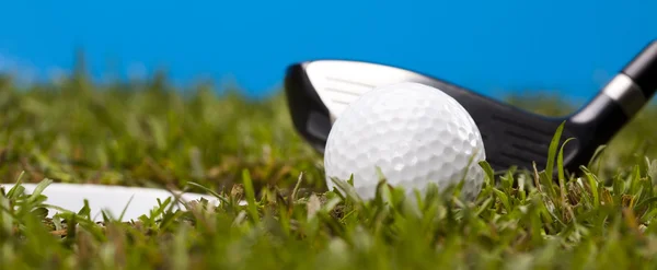 Pelota de golf sobre hierba verde sobre fondo azul —  Fotos de Stock