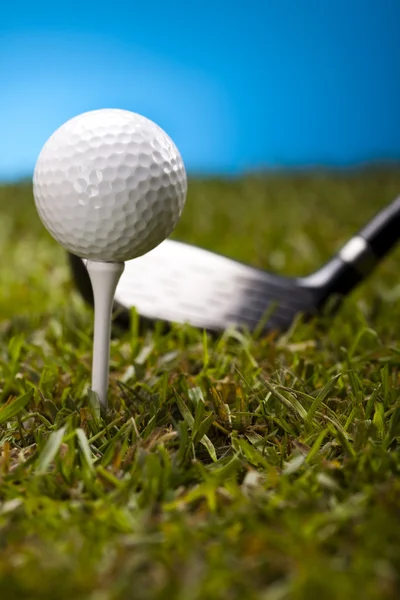 Golf ball on green grass over a blue background — Stock Photo, Image