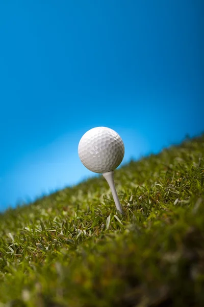 Golf ball on green grass over a blue background — Stock Photo, Image