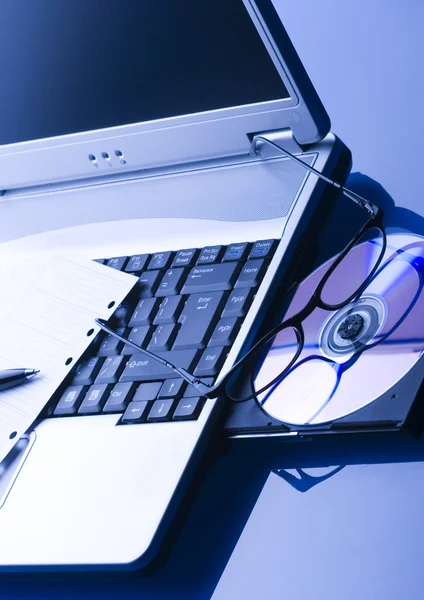 Laptop with a disc & glasses — Stock Photo, Image
