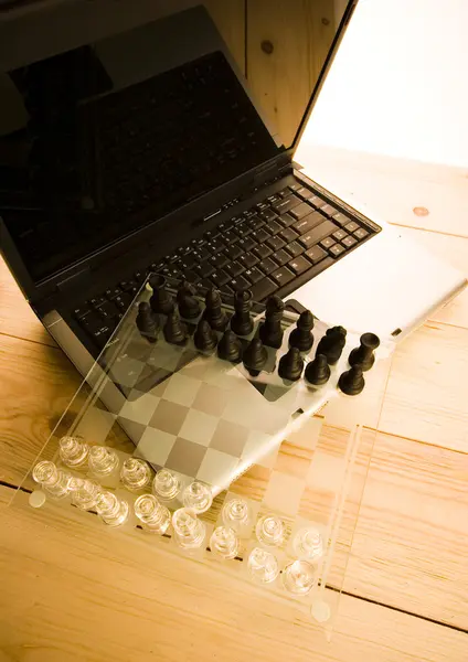 Стеклянные шахматы с ноутбуком — стоковое фото