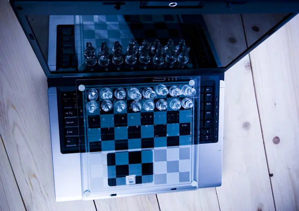 Стеклянные шахматы с ноутбуком — стоковое фото