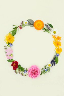 Summer wreath with herbs and flowers. Flora for naturopathic herbal plant medicine, seasoning and food decoration. On natural hemp paper background. Top view, flat lay, copy space.