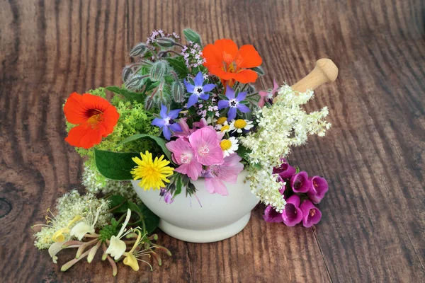 Edible flowers and herbs for natural plant based herbal medicine remedies and food decoration in a mortar. Alternative health and wellness concept. On rustic wood background.